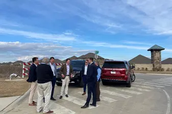 Sieben Männer stehen auf einem Parkplatz vor zwei SUVs