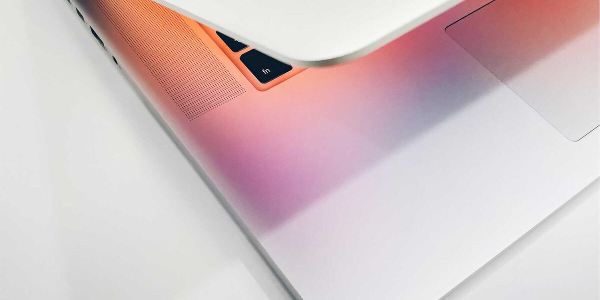 Ein MacBook fotografiert im angeschnittenen Winkel. Der Bildschirm zeigt Pfirsich bis Zyan Farben an.