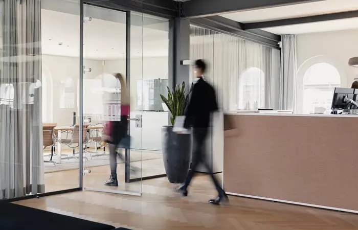 Büro Glaswand Menschen Menschen gehen durch das Kontora Family Office, die Aufnahme ist verschwommen.
