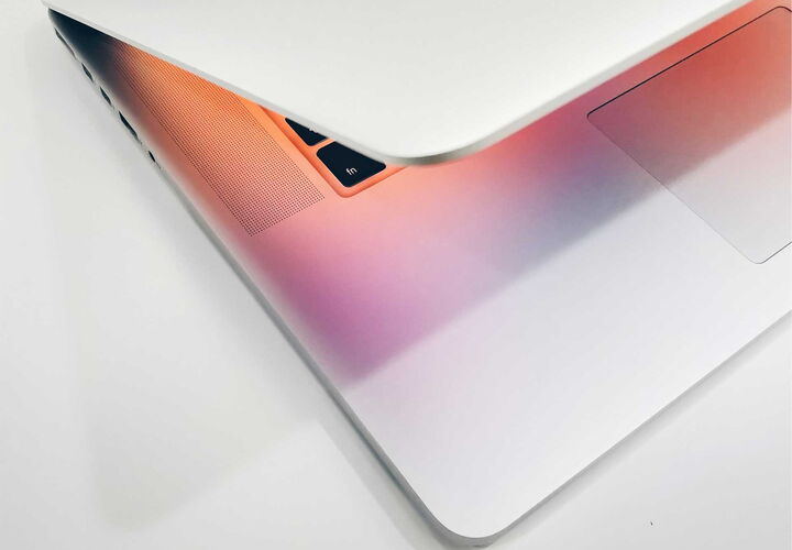 MacBook A MacBook fotographed in a cut angle. The screen emitts cyan and peach colours